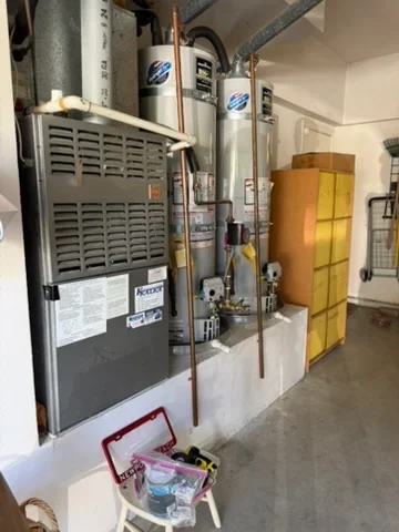 Multiple water heaters and HVAC units with copper piping and venting installed in utility room