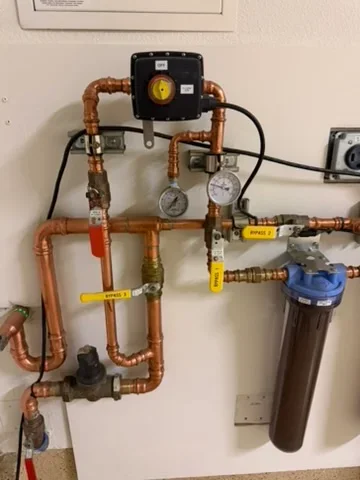 Copper piping water filtration system with dual filters, pressure gauges, and automated control valve
